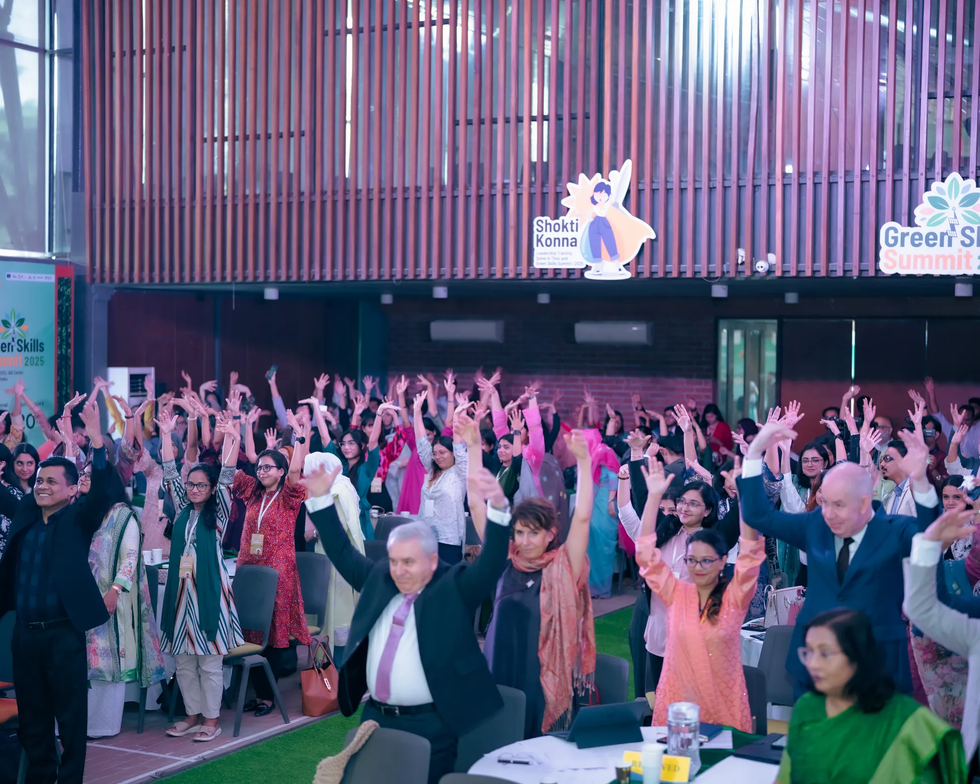 Participants and guests raising their hands together at the Green Skills Summit 2025
